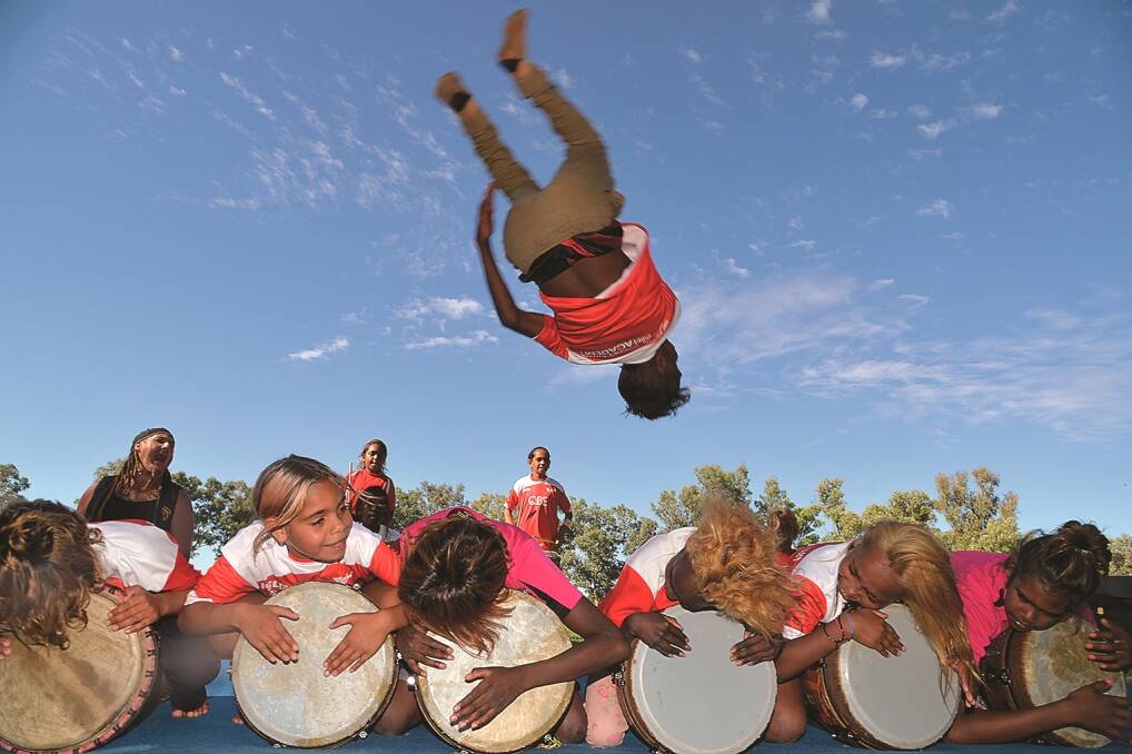 The Mutitjulu Ninja Circus performs over the heads of members of Drum Atweme. Photo courtesy Ayers Rock Resort.