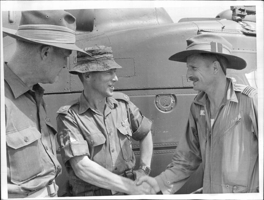 Major Harry Smith (centre), Commanding officer of "D" Company, 6th R.A.R., shakes hands with Flight-Lieutenant Cliff Dohle in appreciation of the work of R.A.A.F. helicopter pilots in the battle of Long Tan. Group-Captain Peter Raw, Commanding officer of the R.A.A.F. Element, Australian task force, Vietnam, looks on. The photo was taken on September 03, 1966.