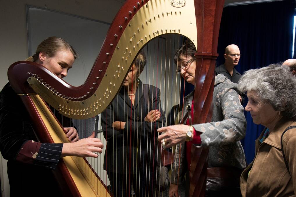 MUSIC TO THEIR EARS – Harp and Education and Ensembles manager Meriel Owen demonstrates the  instrument to people with hearing loss.