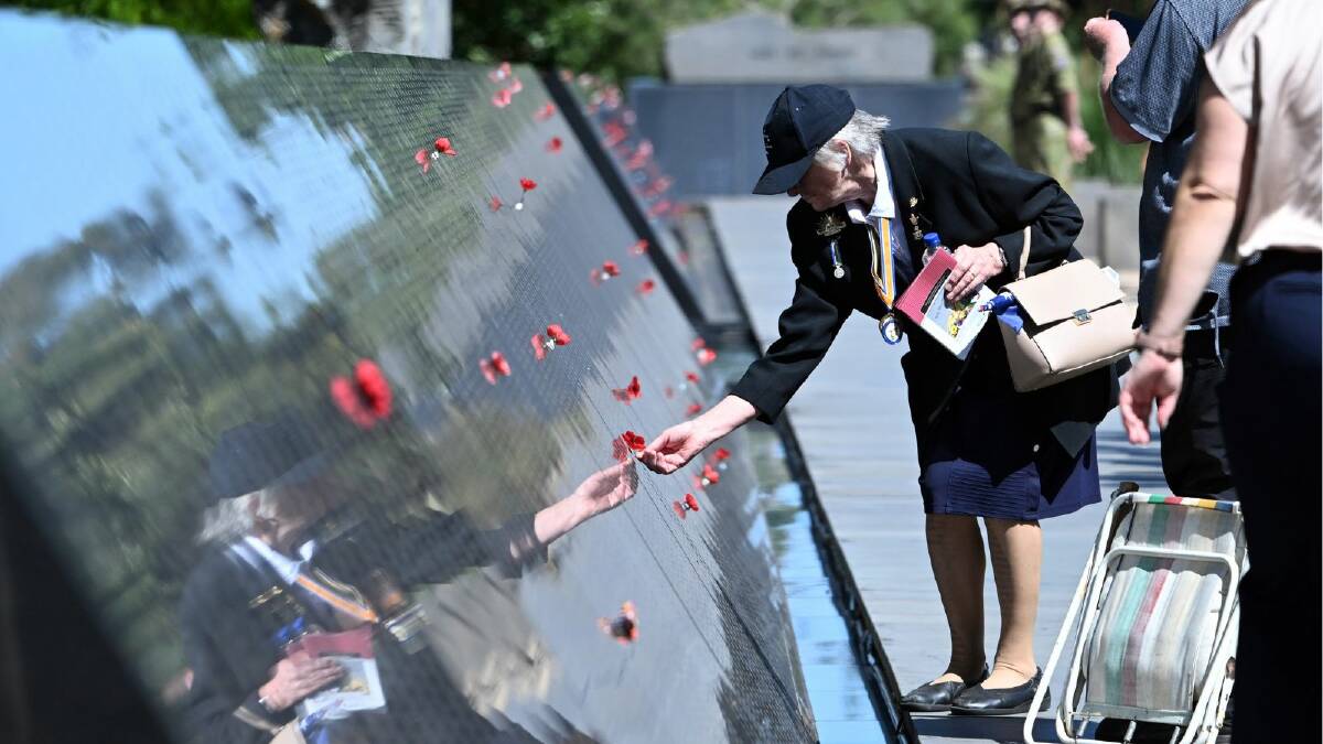 A woman places a poppy on one of the 36,400 names on the Australian Ex-Prisoners of War Memorial in Ballarat's South Gardens. Picture by Kate Healy