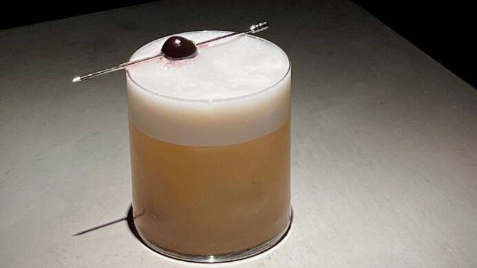 Bourbon whiskey sour garnished with a maraschino cherry. Picture via Gedulgt
