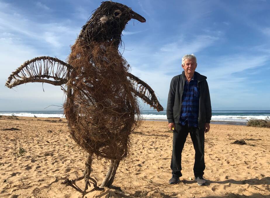 HAPPY FEAT: Peter Rush with his two-metre high Adelie penguin at North Avoca beach on the NSW Central Coast. Photo: Geraldine Cardozo