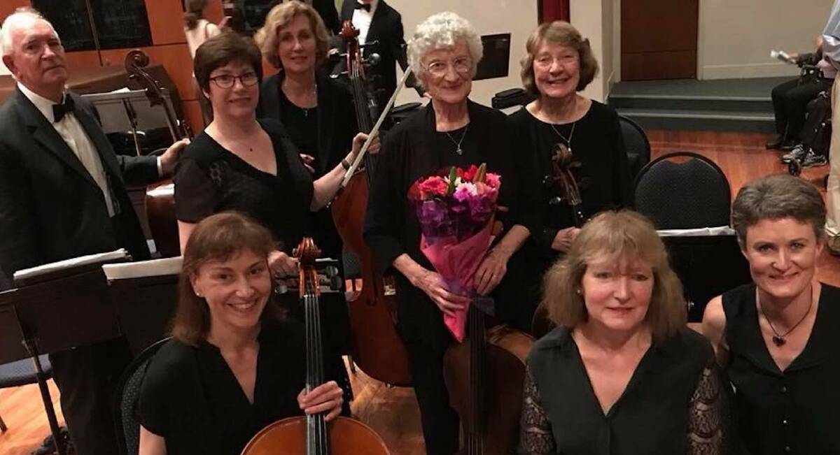 Staying interested: Lois Snibson (holding roses) pictured on her 90th birthday with her fellow cellists from the Surrey Hills orchestra.