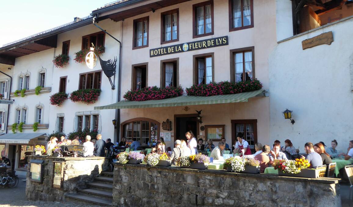 CHOCOLATE-BOX TOWN: Relaxing in the sunshine outside a hotel in Gruyeres.