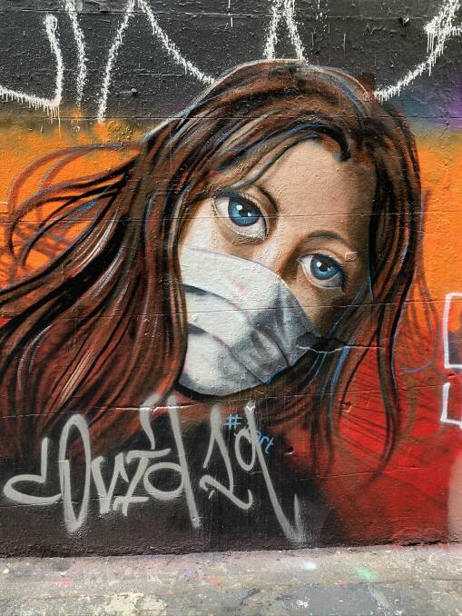 THOSE EYES: A beautiful masked woman by artist John Lawry in Hosier Lane seems to sum up the strange times we are living in today.
