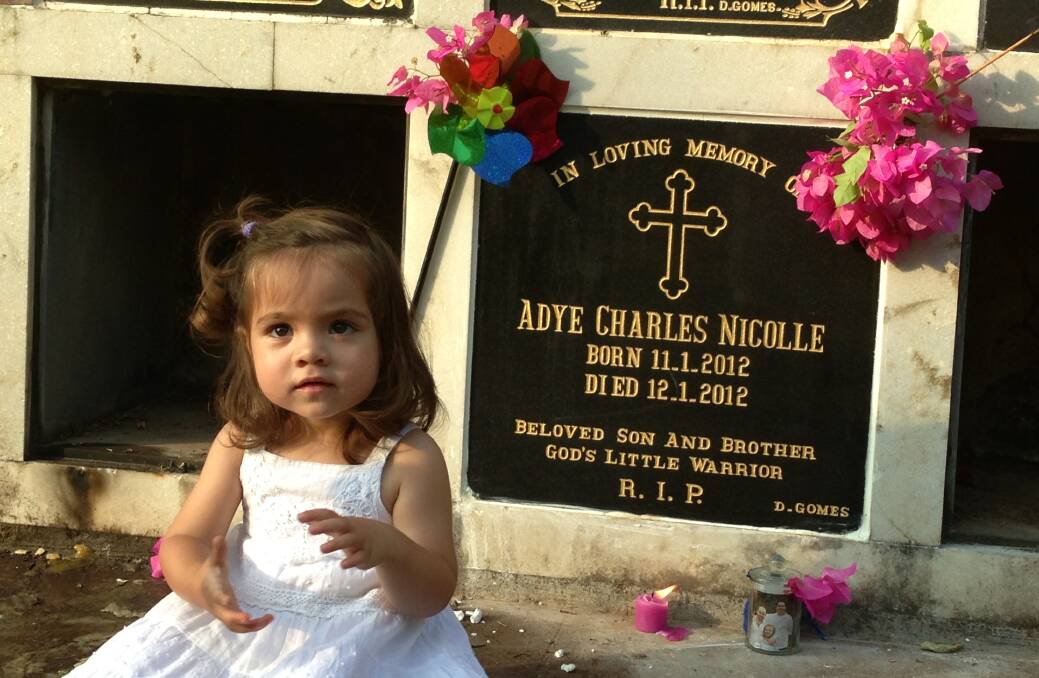 Lilah Nicolle pictured sitting next to the memorial for her brother, Adye. Photo: Supplied.