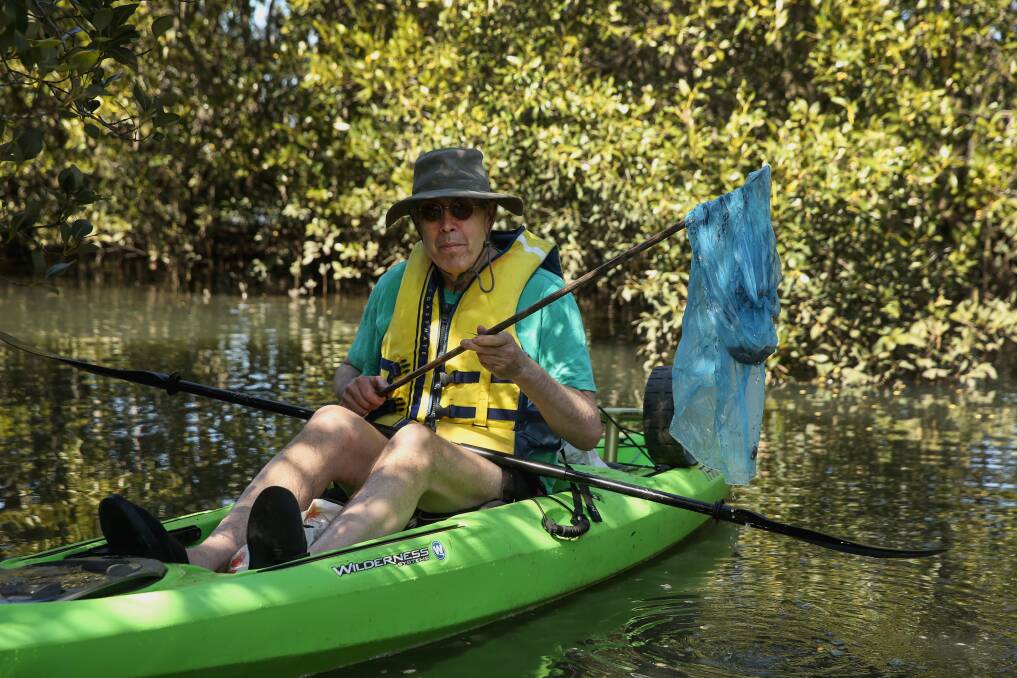 CLEAN-UP KAYAKER: Michael Gormly fishes a plastic bag out of Throsby Creek. Picture: Marina Neil