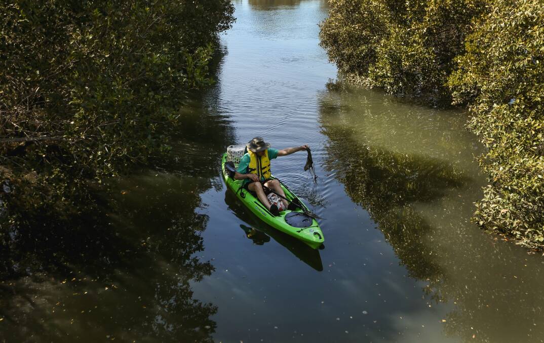 Michael Gormly grabs another piece of plastic out of Throsby Creek. Picture: Marina Neil