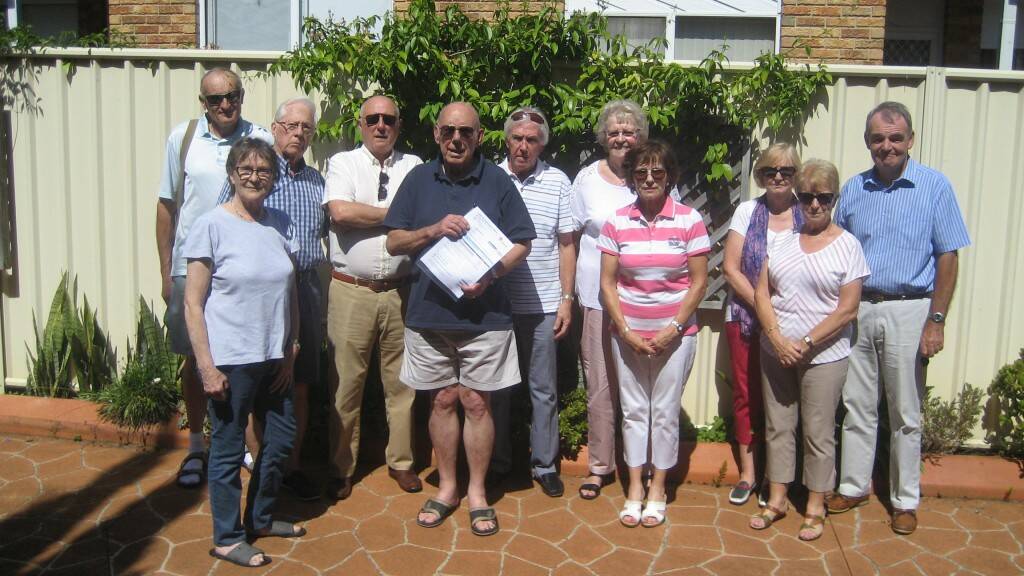 FINANCIAL NIGHTMARE – David Jagoe, of East Gosford, holds his foreign investor land tax surcharge bill. He is joined by other affected expats including Ed Cowie (sixth from the left).