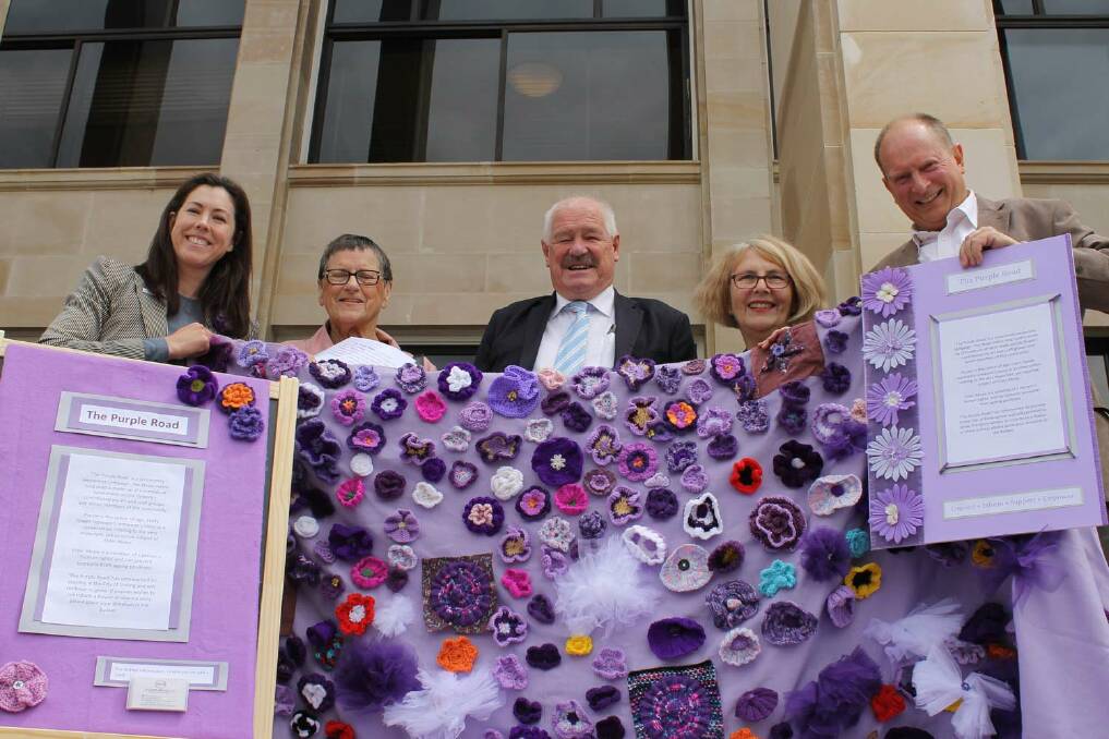 PEERS FOR PURPLE – The purple road with its handmade flowers outside Parliament House is held by (from left) project officer Marissa Martin, Karen Merrin, Seniors and Ageing Minister Mick Murray, peer volunteer Judy Jouhador and project officer Bruce Carstairs.
