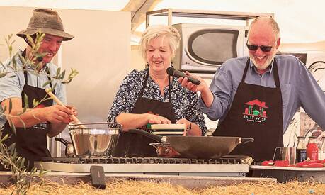 CLOVE OF GOODNESS  – Cookbook author and teacher Sally Wise gets a little help  cooking up a treat at the garlic festival. Photo: Philip Hallam