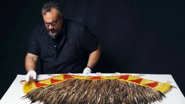Logan Metcalfe, collections officer Pacific at the Australian Museum, examines the feathers of the rare cape given to Captain Cook by a Hawaiian chief. Photo: James Brickwood