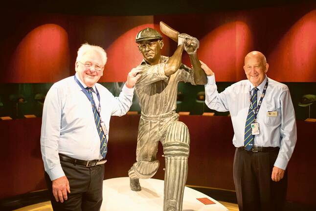 NOT OUT –   National Sports Museum volunteers Alan Holmes and Graeme Cameron with a statue of Don Bradman.