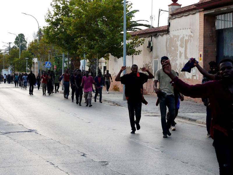 Migrants celebrated as they walked along a street after jumping a Morocco-Spain border fence.