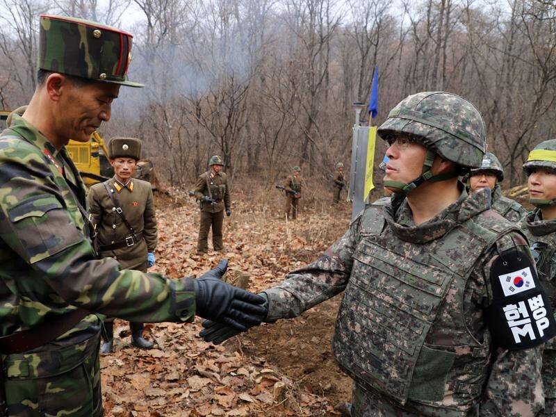 Soldiers from North Korea (left) and South Korea reduce tension with a handshake at the DMZ.